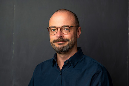 Headshot of Malte Ziewitz in front of an empty blackboard.